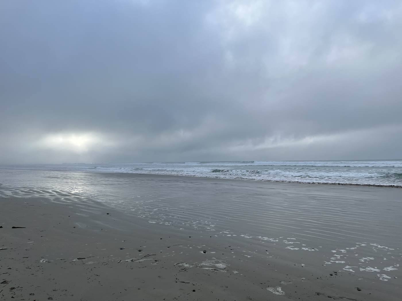 Silbriger Strand unter aufreißender Wolkendecke